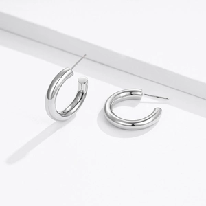 Detailed close-up of silver C-shaped hoop earrings with a polished glossy finish