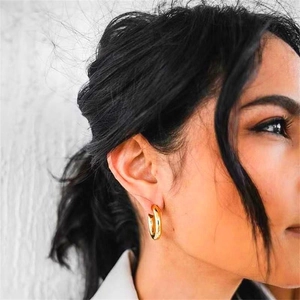 Close-up of polished gold hollow C-shaped hoop earrings worn by a model