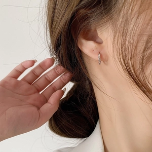 Close-up of S925 sterling silver geometric hoop earrings with twisted texture on a model