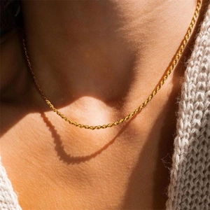 Gros plan d'un collier chaîne torsadée dorée sur un modèle montrant les détails