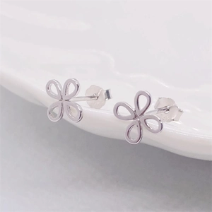 Minimalist S925 sterling silver hollow clover stud earrings on a white ceramic plate