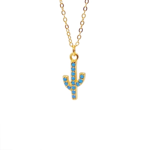Detailed close-up of a cactus pendant necklace with gold plating and blue stone inlay