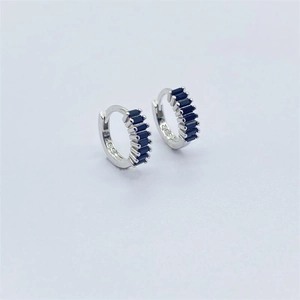 Dettaglio macro di orecchini a cerchio in argento 925 con pietre baguette blu incassate