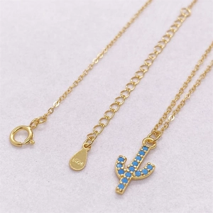 Detailed macro view of S925 sterling silver cactus pendant with blue stone and gold chain