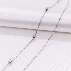 Macro detail of S925 sterling silver double layer anklet with polished beads on silk