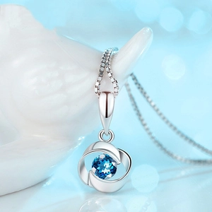 Gros plan du pendentif rose tournant en argent S925 avec une pierre précieuse bleue