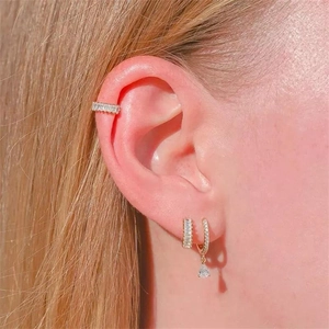Primo piano di orecchini a cerchio in argento S925 dorato con zircone scintillante sull'orecchio