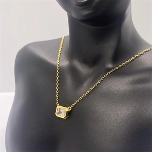 Detail of a dainty gold necklace featuring a rectangular zircon pendant on a black bust