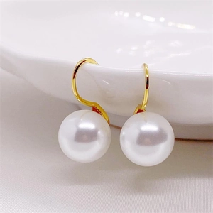 Elegant gold S925 silver pearl drop earrings hanging on a white ceramic edge