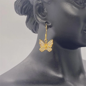 Macro detail of gold butterfly drop earring featuring shimmering paved cubic zirconia wings