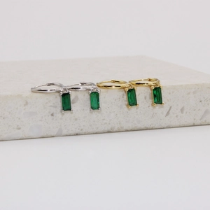 Detalle de pendientes de aro de plata S925 con circonitas verdes de corte esmeralda