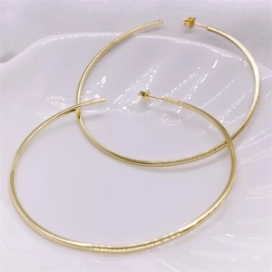 Large golden hoop earrings in S925 sterling silver on a white ceramic display plate