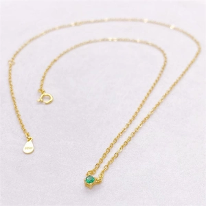 Macro view of S925 hallmark on gold-plated silver chain with green zircon stone pendant