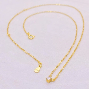 Close-up of S925 hallmark on gold plated silver necklace with a green zircon stone