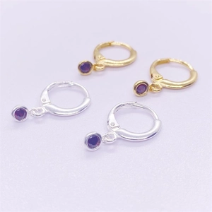 Détail de créoles en argent et or avec pendentifs ronds en zircone violette