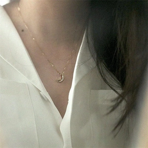 Gros plan d'un collier pendentif lune croissante dorée sur une chaîne à perles fine