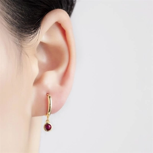 Gros plan d'une boucle d'oreille en argent S925 doré avec zircon rond rouge