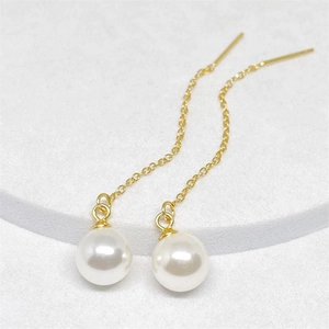 Detailed view of long gold tassel earrings with elegant round white pearls on a stone base