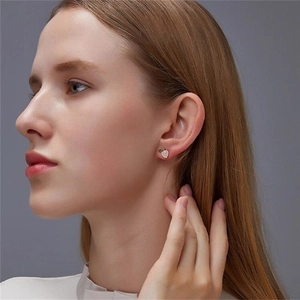 Close-up of a cute S925 silver peach earring with pink enamel and a green leaf detail
