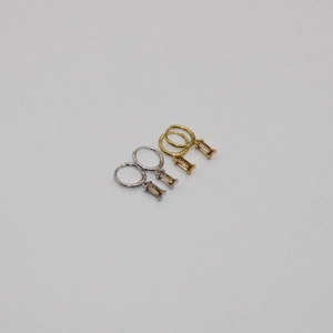 Detalle de pendientes huggie de plata S925 y oro con circonitas rectangulares