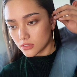 Macro side view of model wearing large polished gold S925 sterling silver hoop earrings