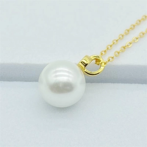 Macro view of a large white pearl pendant with a polished gold finish connection