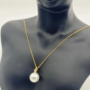 Close-up of a S925 silver pearl pendant with a sparkling diamond on a gold chain
