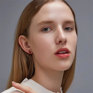 Gros plan de boucles d'oreilles fraises en argent S925 portées par un modèle