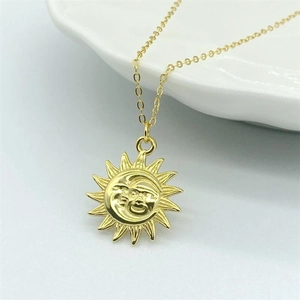 Vue détaillée d'un pendentif soleil et lune doré avec un design gravé bohème