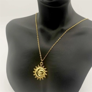 Détail du pendentif soleil et lune doré sur mannequin noir avec chaîne fine