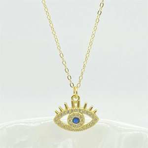 Detail of gold evil eye pendant with blue gemstone and pavé stones on ceramic edge