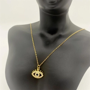 Detail of gold evil eye pendant with blue crystal on a black mannequin display stand