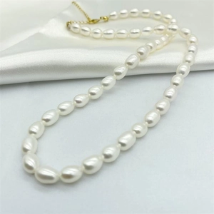 Elegant natural freshwater pearl necklace with gold clasp on white silk background