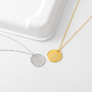 Detail of silver hammered texture and gold polished mirror finish round pendants