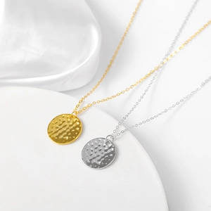 Macro shot of gold and silver hammered coin pendants on satin background