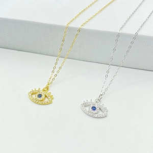 Macro view of gold and silver evil eye pendants with sparkling blue zircons