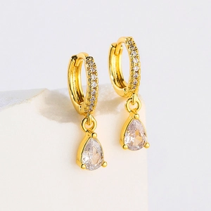 Close-up of gold hoop earrings with small diamonds and a three-claw pear-cut zircon pendant