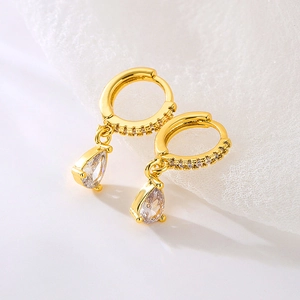 Macro detail of gold pear-cut zircon drop earring with a three-claw setting and pavé accents