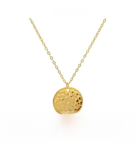 Macro shot of minimalist gold round pendant with hammered texture and thin O-chain necklace