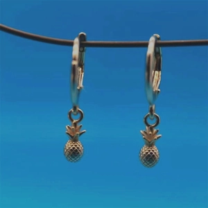 Detail of s925 gold-plated pineapple hoop earrings hanging on a blue background