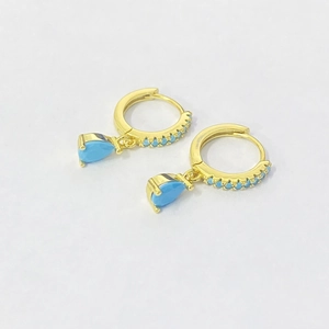 Detail of gold drop earrings featuring sky blue teardrop stones and pavé accents