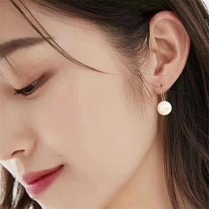 Minimalist S925 sterling silver pearl hook earring worn by a model in warm lighting
