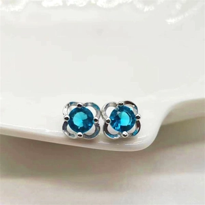Macro shot of silver four-leaf clover stud earrings with round blue sapphire zircon centers