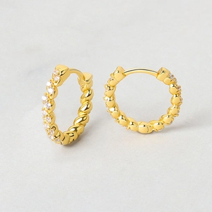 Close-up of twisted gold hoop earrings featuring micro-pave white cubic zirconia stones