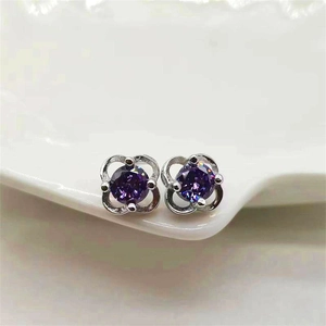 Close-up of purple round-cut zircon stud earrings with silver four-prong clover setting