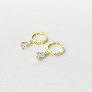 Detail of gold hoop earrings featuring pear-cut white zircon drops and paved stones