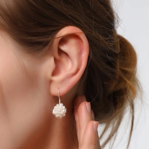 Macro detail of hand-woven freshwater pearl cluster earrings on a model's ear