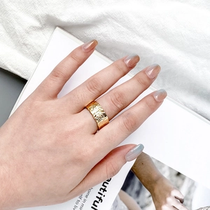 Detailed view of irregular hammered texture on a wide gold-plated open ring for women