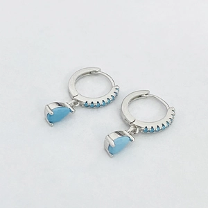 Detailed view of silver hoop earrings featuring blue zircon pavé and teardrop pendants
