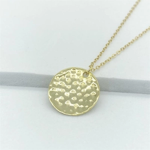 Elegant gold hammered round pendant necklace with wavy texture on white tiered background